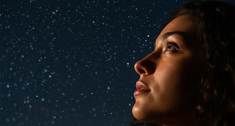 Sente demais? 5 sinais de que sua mediunidade está despertando 1 Mulher olhando para o céu estrelado, em um momento de conexão com sua intuição e espiritualidade.